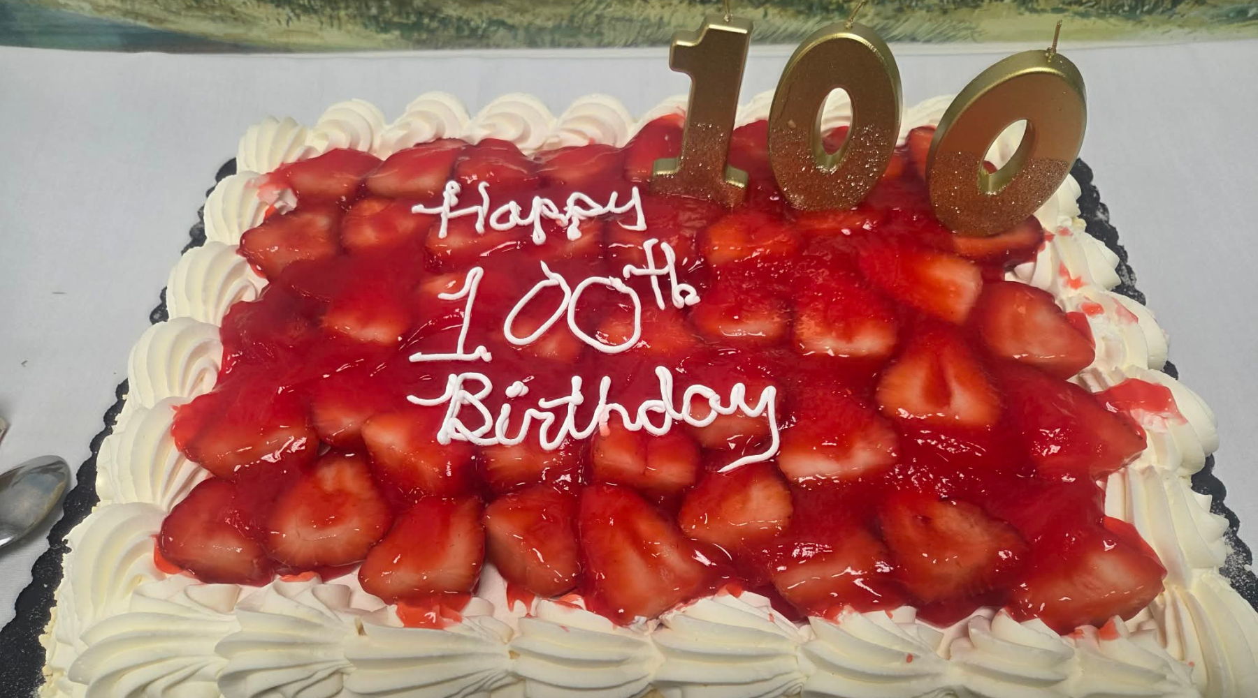 Rectangular strawberry cake with Happy 100th Birthday written on top, gold 100 candles, and a sweet touch perfect for celebrating in winter or cheering up during cold and flu season.