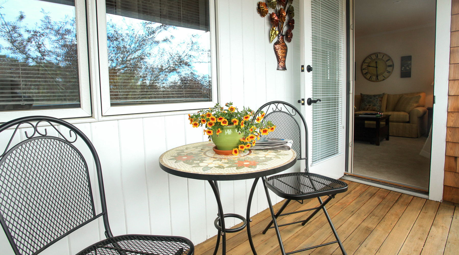outside deck with two metal chairs and a table with flowers