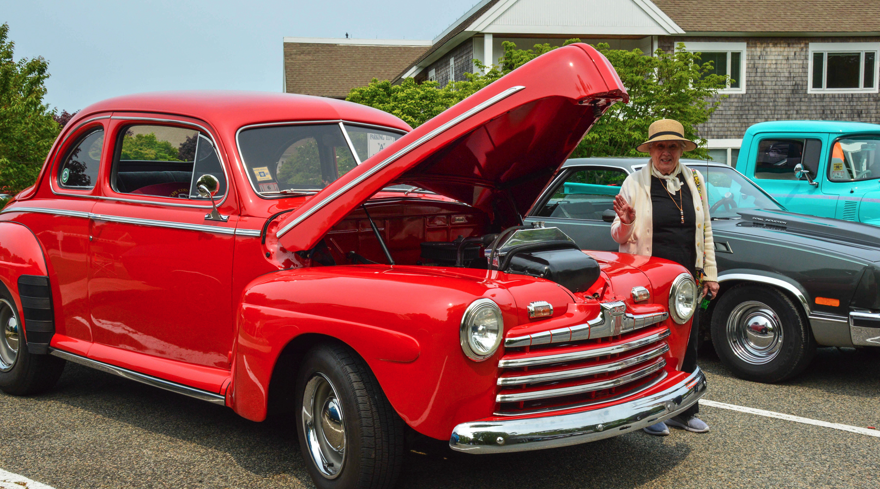 woman standing next to a classic red American car