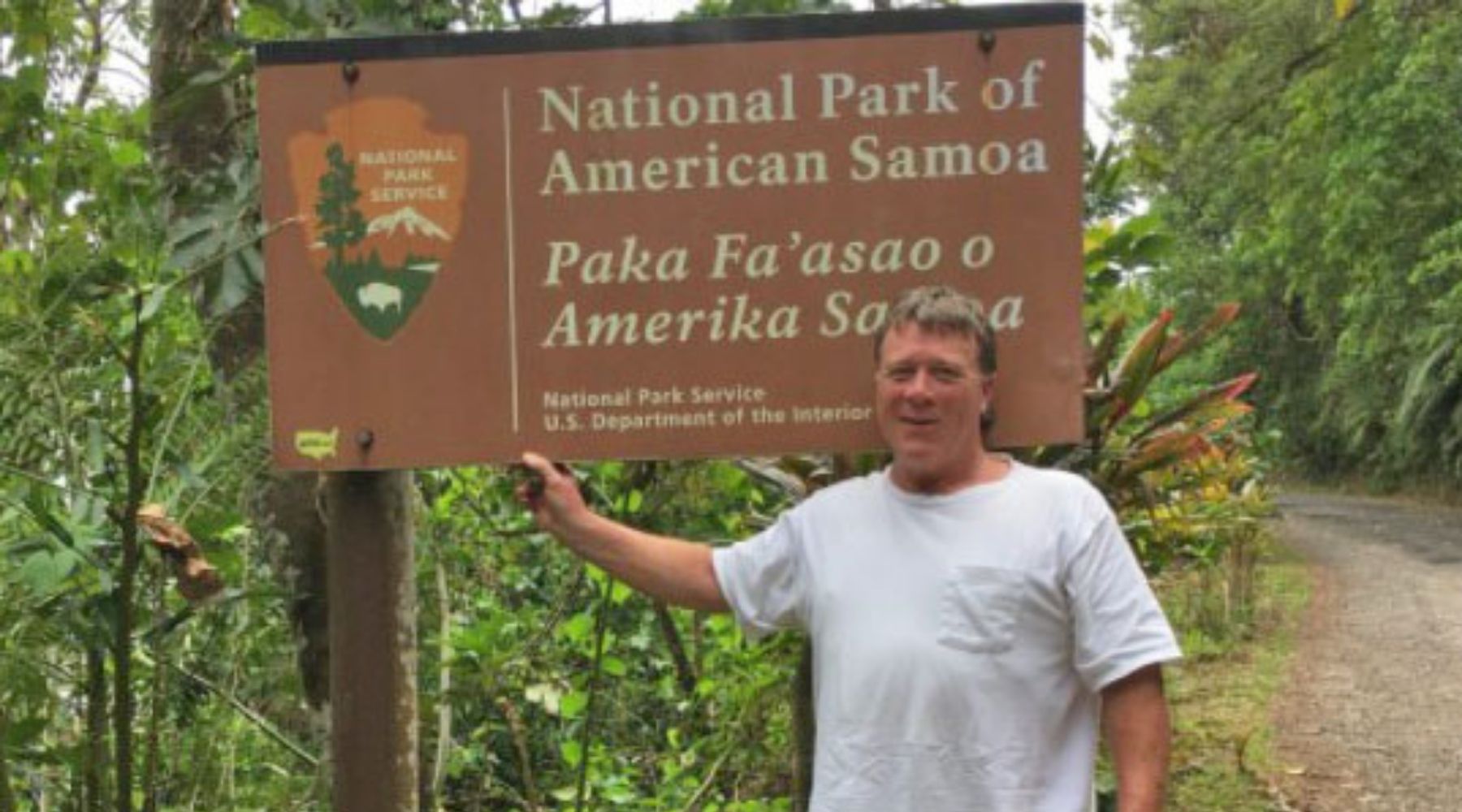 man standing in front of a national park sign