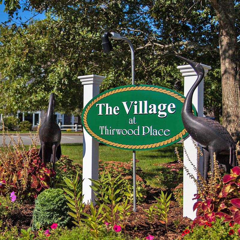 The Village at Thirwood Place sign surrounded by flowers on a sunny day