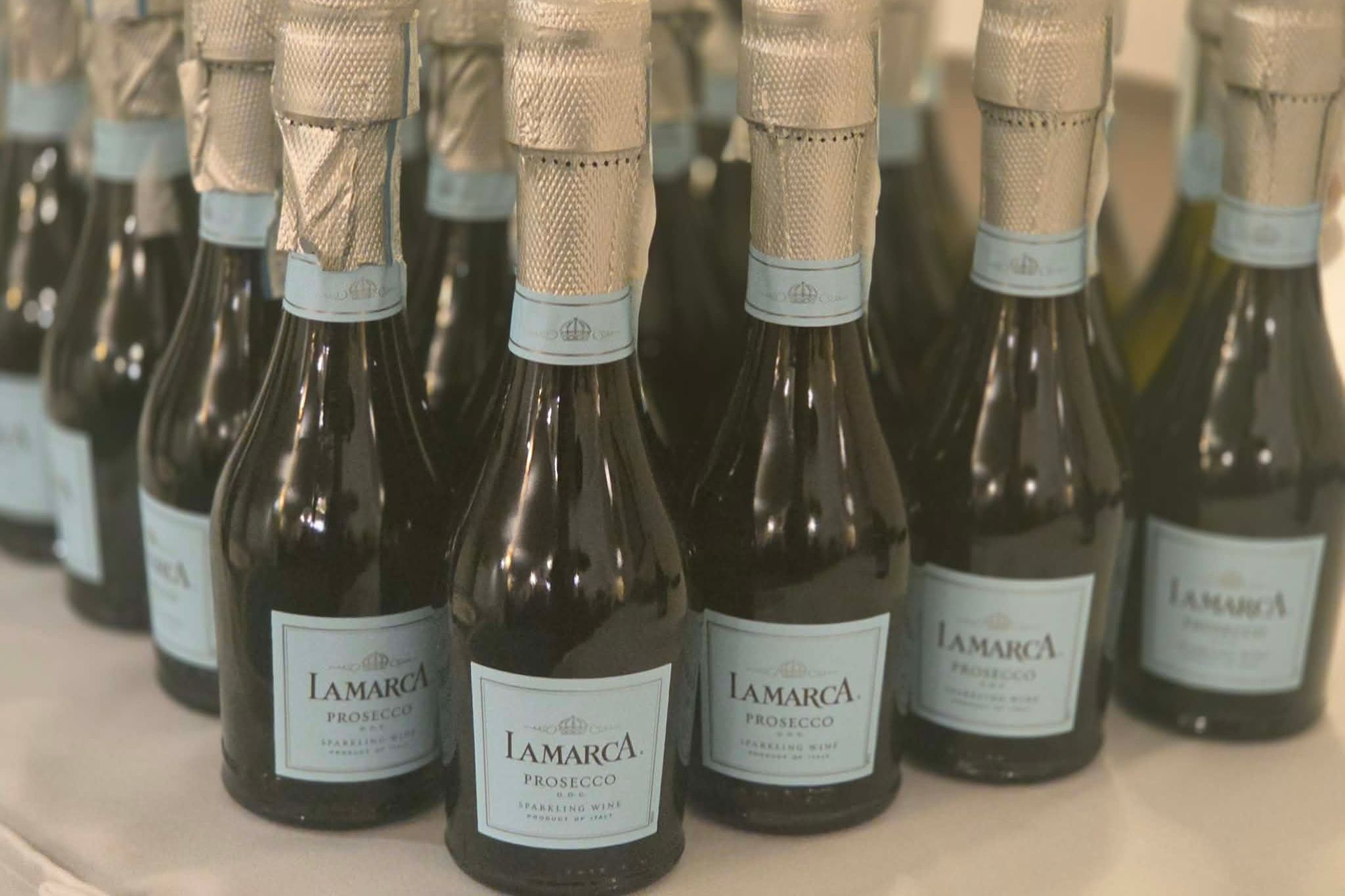 Mini bottles of La Marca Prosecco sparkling wine arranged closely together on a table, perfect for capturing the essence of summer in a festive photo essay.