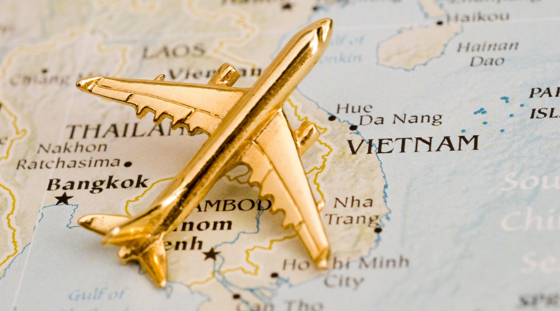 A gold airplane model is placed on a map highlighting Vietnam, Cambodia, Thailand, and surrounding areas, with animal illustrations accentuating the region’s rich biodiversity.