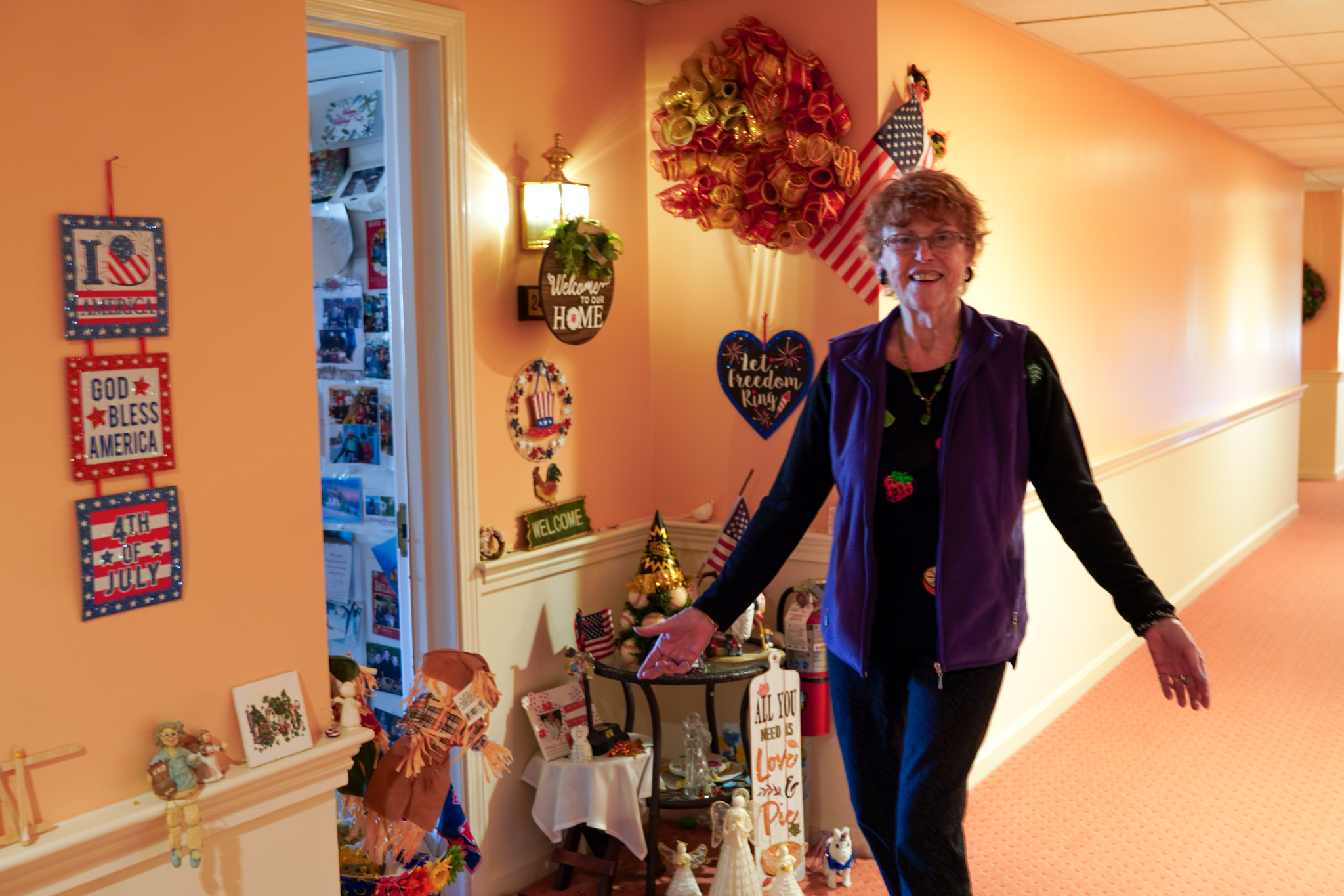 A smiling woman stands in a decorated hallway buzzing with patriotic and welcoming signs.
