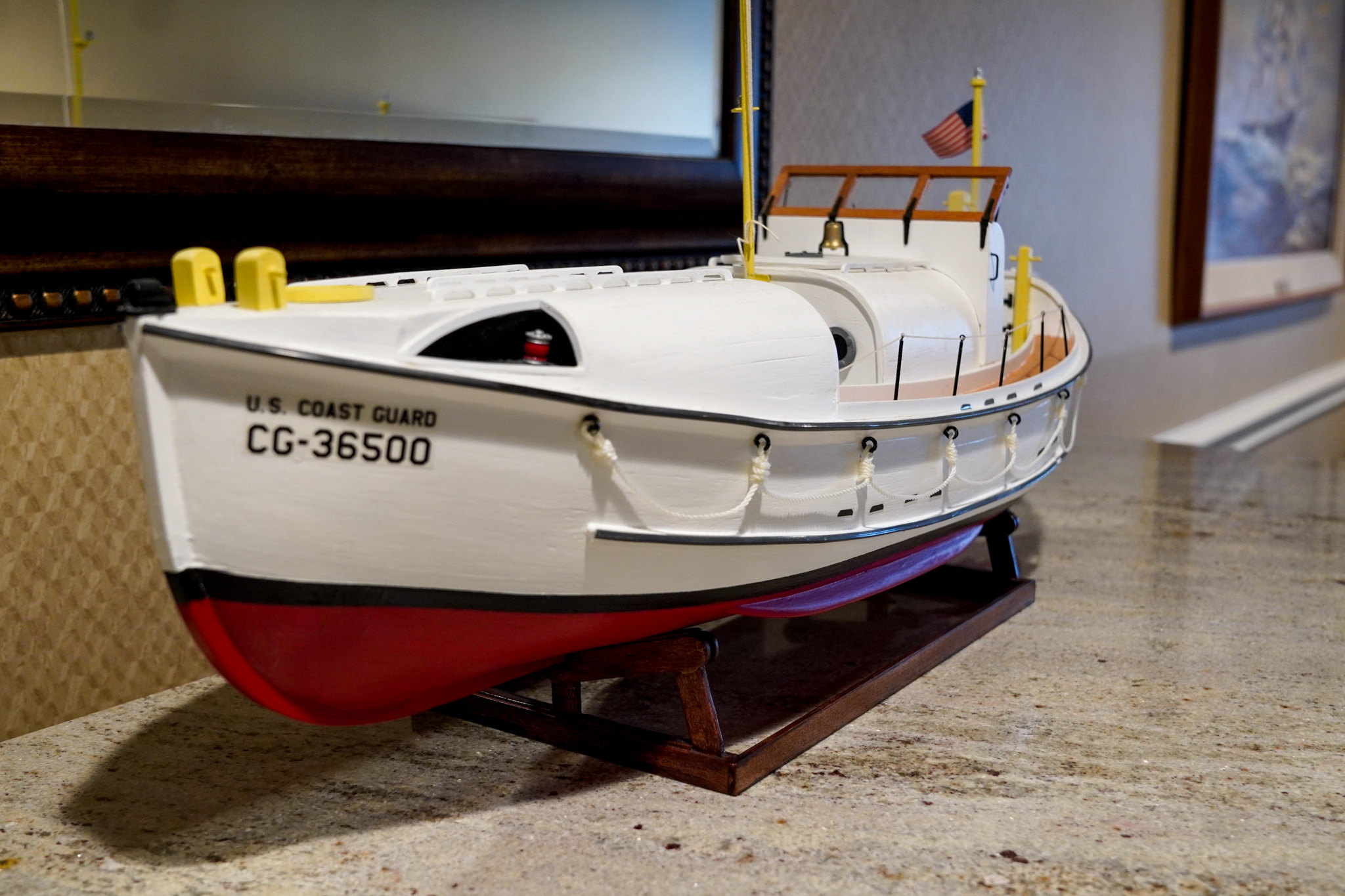 Model of U.S. Coast Guard boat CG-36500 on a display stand, its red and white hull evoking memories of maritime rescues, perfect for adding a nautical touch to any senior living space.