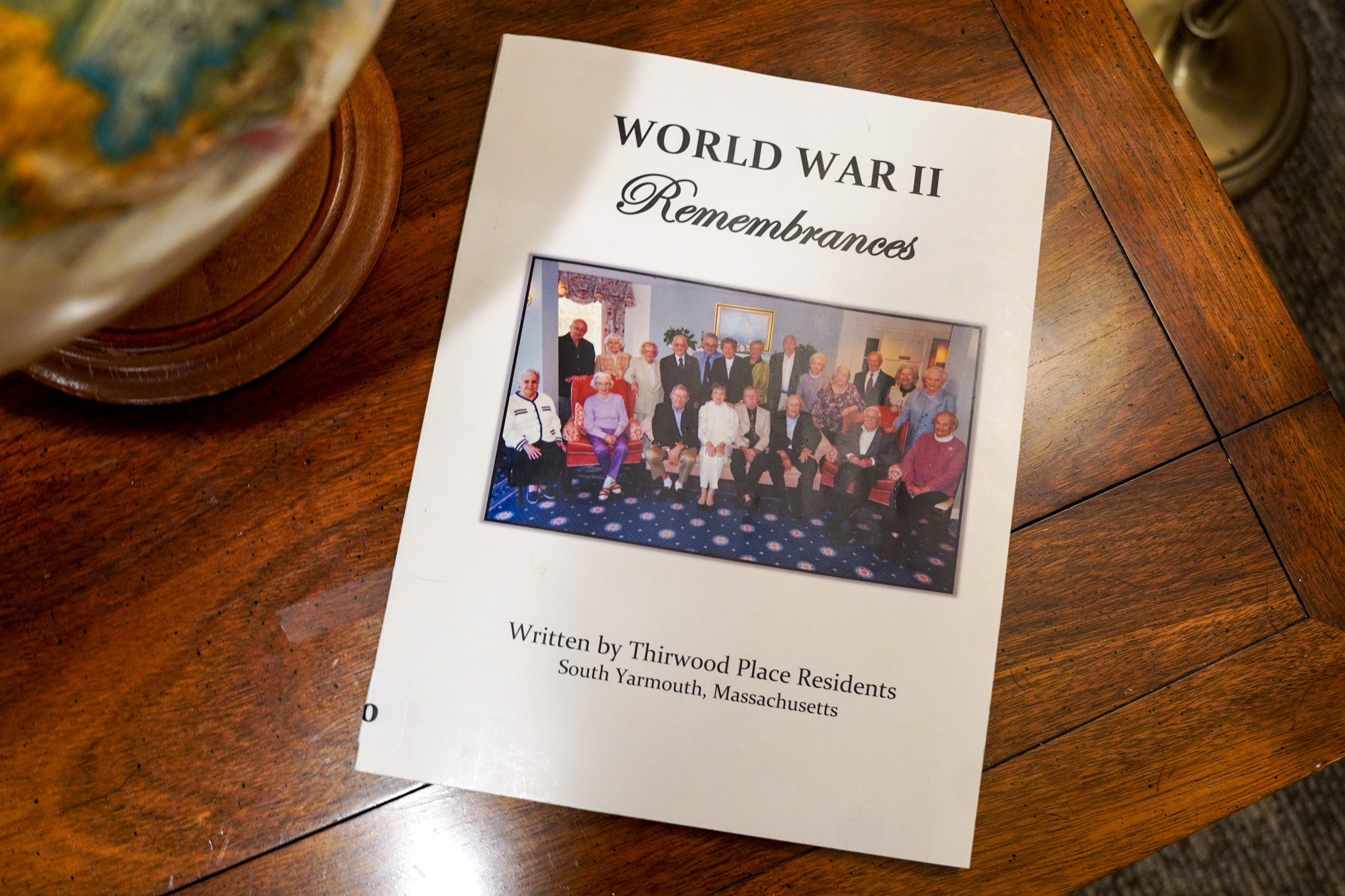 Book titled World War II Remembrances resting on a wooden table, featuring a group photo on the cover, ready to unfold its stories.