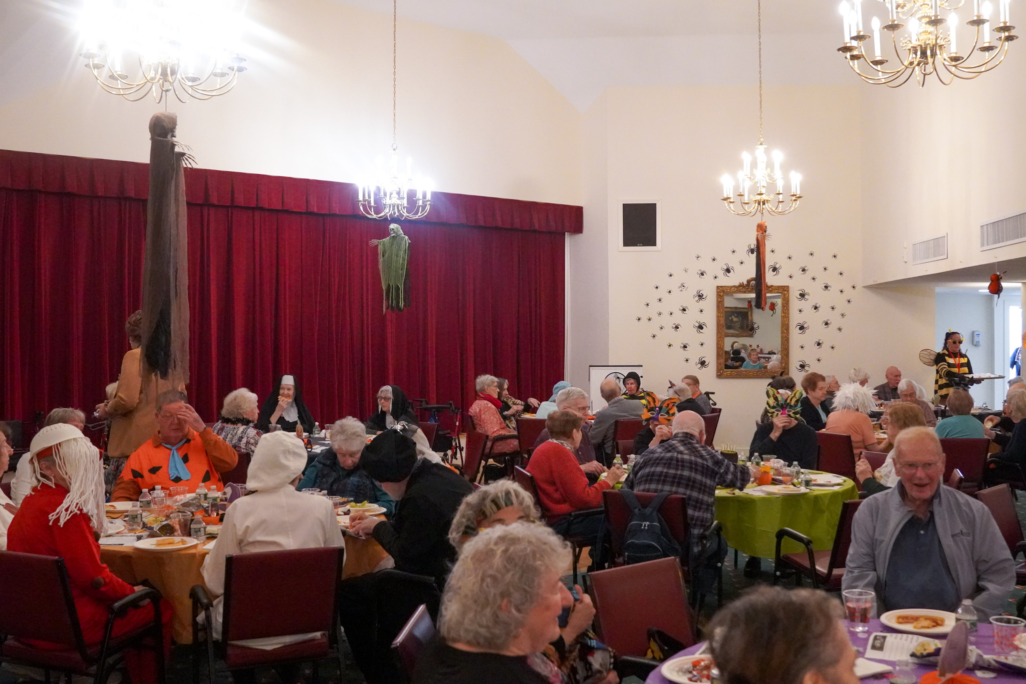 A group of people, gathered for a scholarship meeting, sit at tables in a room.