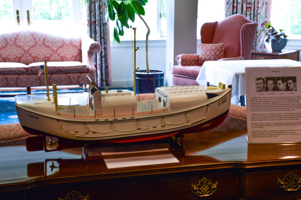 A model of a ship is displayed on a wooden table, accompanied by detailed text and photos, all set within a tastefully furnished room.