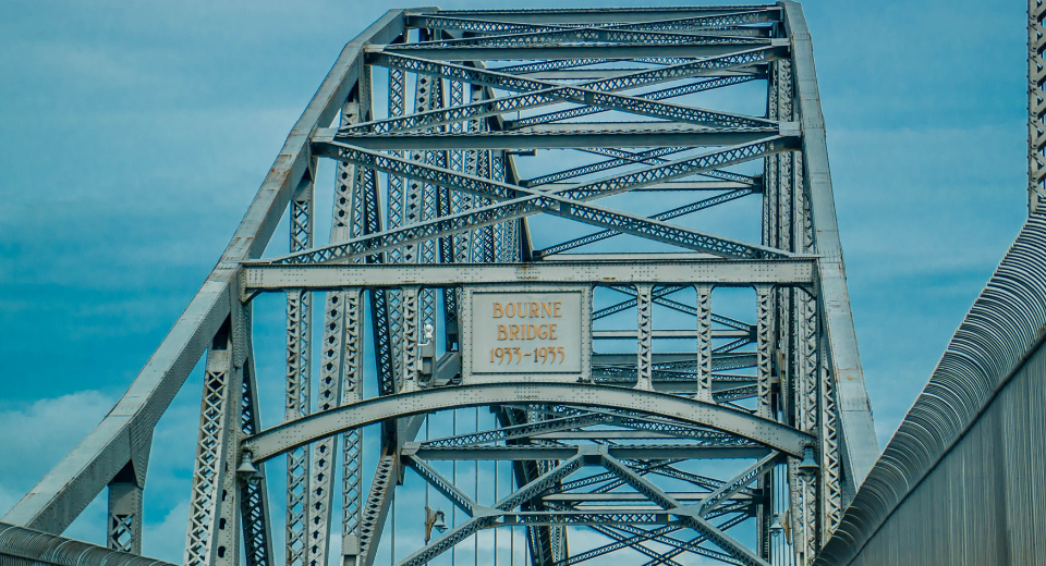 Close-up view of the steel structure of the Bourne Bridge against a blue sky, its design as enduring and supportive as a thriving senior living community.