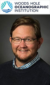 Smiling man with glasses and beard, wearing sweater; Woods Hole Oceanographic Institution logo above.