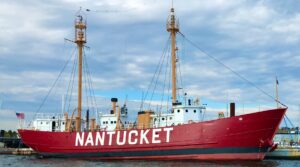 A red ship labeled Nantucket is docked in the water under a cloudy sky, standing as steadfast as a nurse during a long night shift.