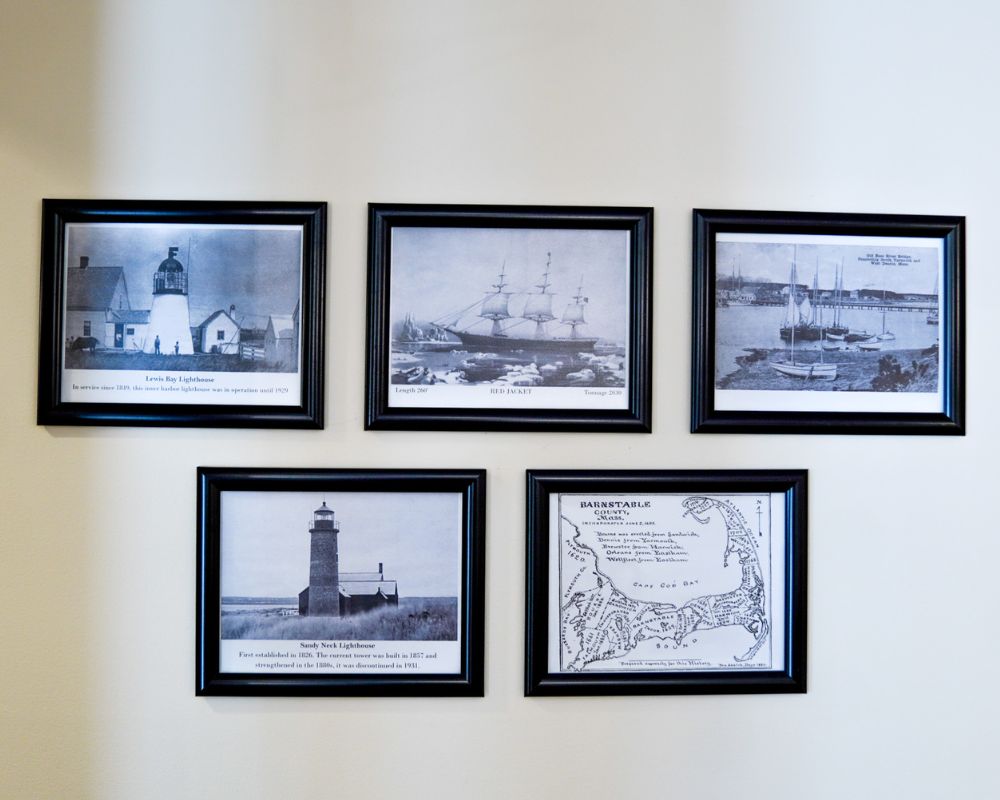 Five framed black and white photographs of lighthouses and ships bring a nostalgic charm to a light-colored wall, perfect for adding a touch of nautical elegance to any senior living space.